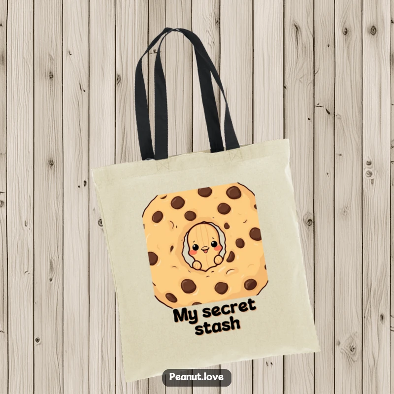 Funny tote bag featuring a peanut character peeking from behind a giant chocolate chip cookie, a humorous and practical accessory.